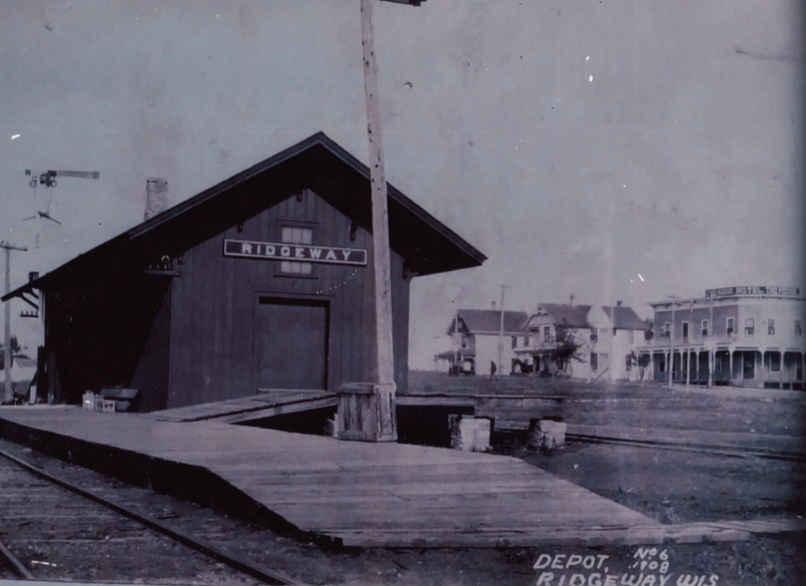 Depot in 1908. In the background is The Ridge Hotel, the house that was moved before the street was cut down. The next house was Dr. Hamilton's office. Notice the special wagon parked out front.