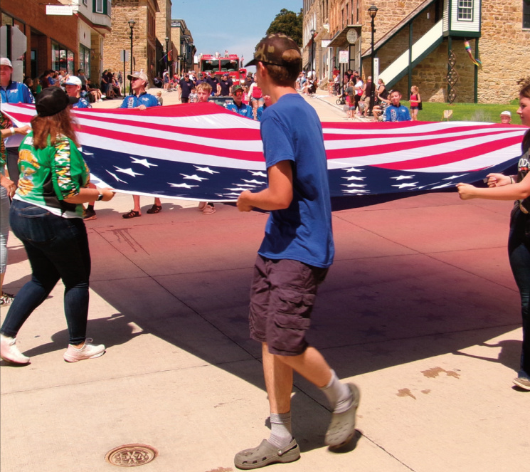 People carrying a large American flag during a parade.