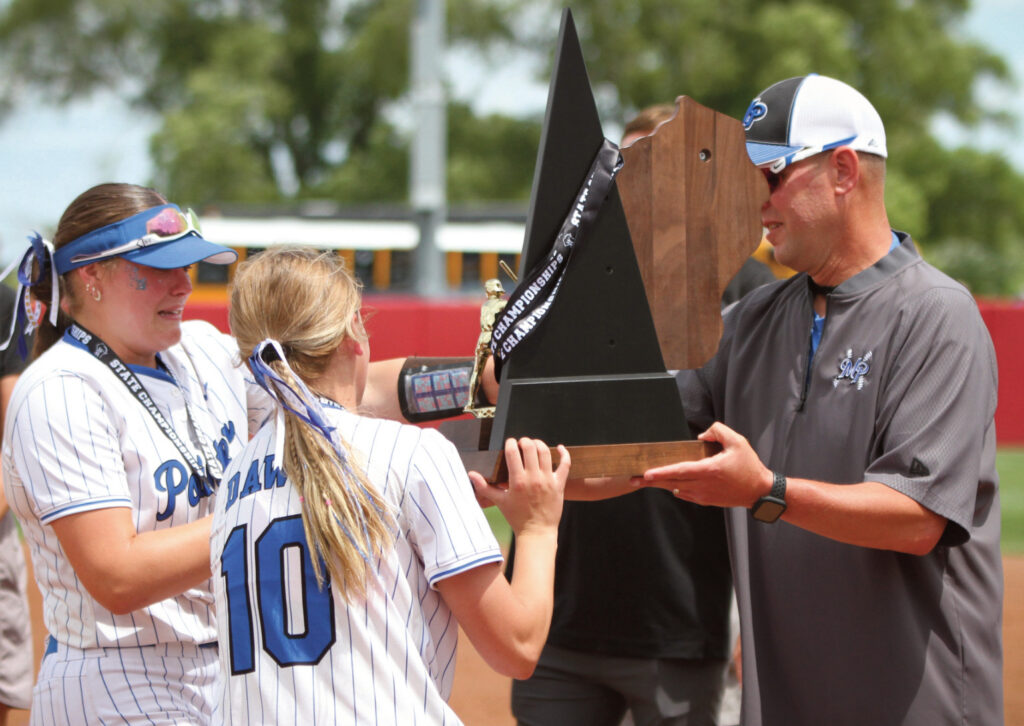 Pointers seniors Maddy Kabat and Jadyn Schults take the championship trophy from Coach Quinn Schultz