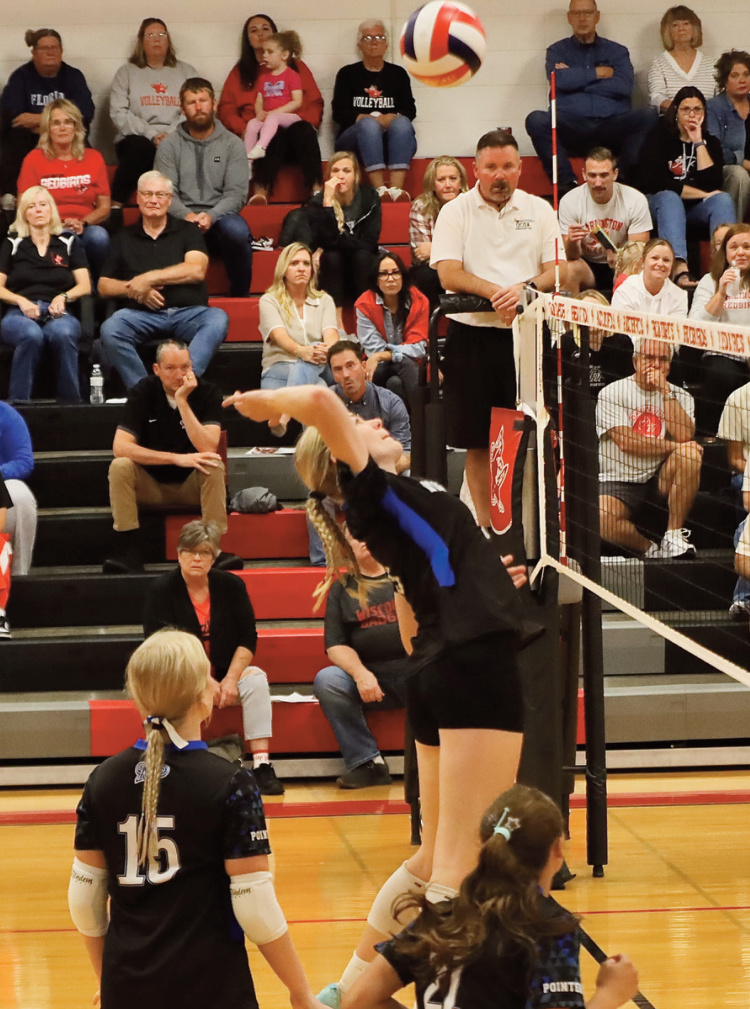 Pointer Kinlee Prust goes high for a spike with Sadie Miller (15) and Tenleigh Bockhop watching the play. Photo by Tori Carey.